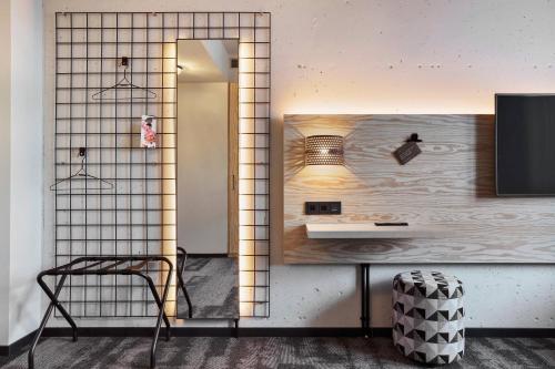 a room with a mirror and a table and a chair at Moxy Frankfurt Airport Kelsterbach in Kelsterbach