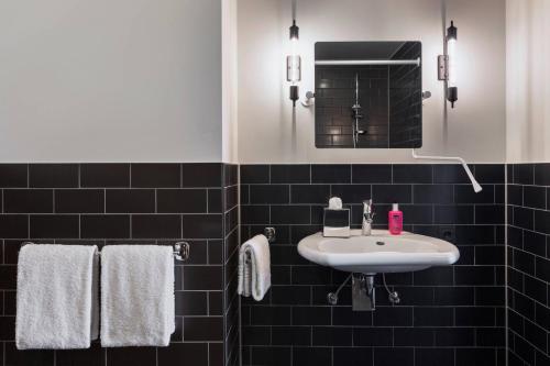 a bathroom with a sink and a mirror and towels at Moxy Frankfurt Airport Kelsterbach in Kelsterbach