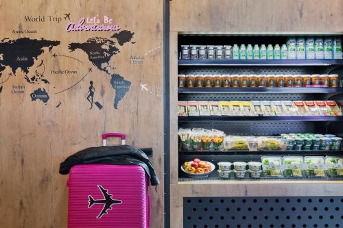 a pink suitcase is sitting in front of a refrigerator at Moxy Frankfurt Airport Kelsterbach in Kelsterbach
