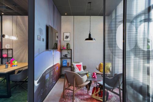 a home office with a desk and chairs and a table at Moxy Frankfurt Airport Kelsterbach in Kelsterbach