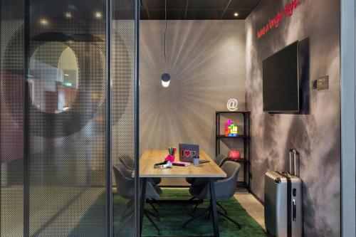 a small table and chairs in a room with a television at Moxy Frankfurt Airport Kelsterbach in Kelsterbach