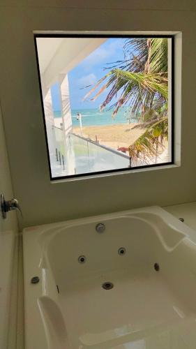 a bath tub in a bathroom with a view of the beach at Pousada Casa Branca in Extremóz