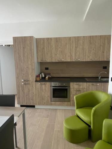 a living room with a green chair and a kitchen at B&B Le Scintille in San Ginesio