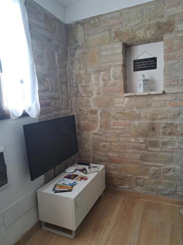 a living room with a tv and a brick wall at B&B Le Scintille in San Ginesio