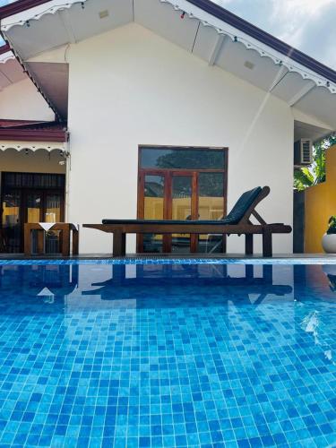 a pool with a table and a bench next to it at Kingz Kottage in Negombo