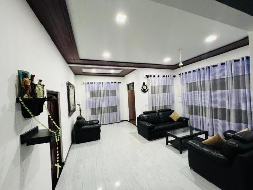 a living room with black leather couches and windows at Kingz Kottage in Negombo