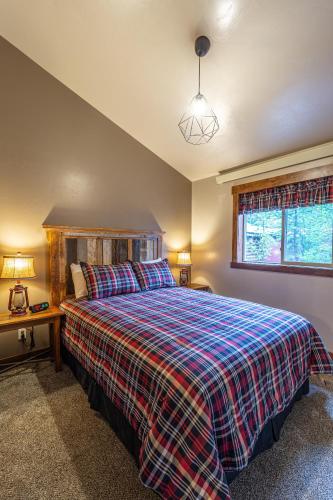a bedroom with a large bed with a plaid blanket at Whiskey Springs Cabin in West Yellowstone