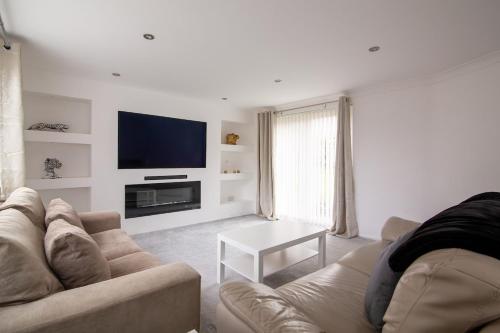 a living room with a couch and a tv at Saintbury House in Glenfield