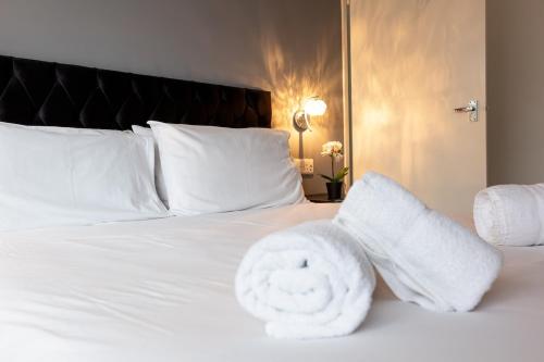 a white bed with a pile of towels on it at Saintbury House in Glenfield