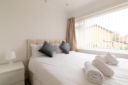 a bedroom with a white bed with pillows and a window at Saintbury House in Glenfield