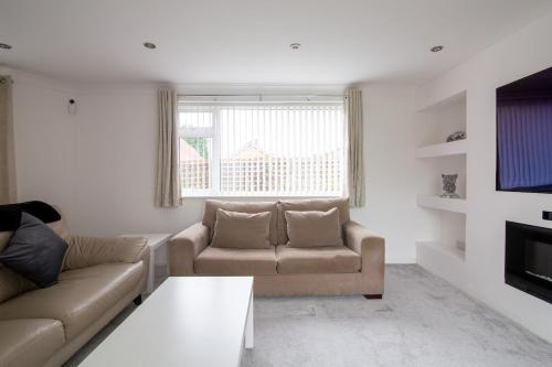 a living room with two couches and a tv at Saintbury House in Glenfield