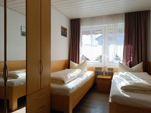 a small room with two beds and a window at 2-Raum FeWo Edelweiß - Hallenbad & Sauna in Fischen