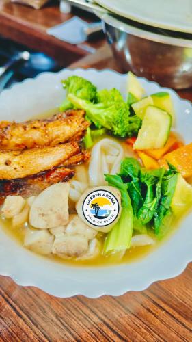 a plate of food with chicken and vegetables on a table at Garden Aroma Palolem, Beachside Hostel & Cafe Bar in Palolem