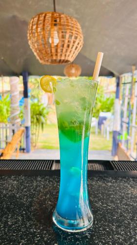 a drink in a blue glass sitting on a table at Garden Aroma Palolem, Beachside Hostel & Cafe Bar in Palolem
