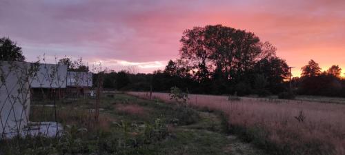 a sunset over a field with a fence and trees at Trappeur in Le Fay