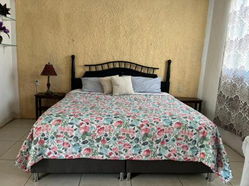 a bedroom with a bed with a floral bedspread at Liah Amplio y Cómodo cuarto privado en Zapopan in Guadalajara
