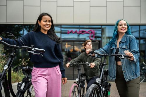 three women walking their bikes down a street at Moxy Utrecht in Utrecht