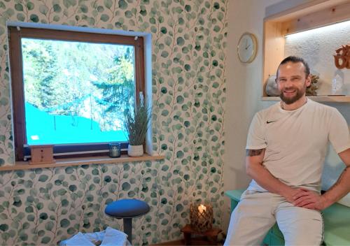 a man sitting on a chair in front of a television at Naturetouch in Steinberg am Rofan