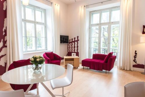 a living room with a table and red chairs at Le Méridien Vienna in Vienna