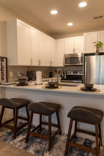 a kitchen with white cabinets and a counter with stools at Home Away from Home in Charlotte