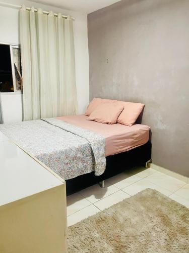 a bedroom with a bed with pink pillows and a window at Apartamento no Centro in Patos