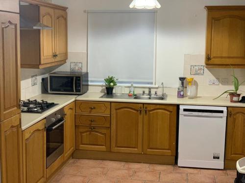 a kitchen with wooden cabinets and a white refrigerator at 4 Bed Room Sharing House in Phibblestown