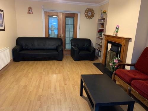 a living room with two black couches and a fireplace at 4 Bed Room Sharing House in Phibblestown