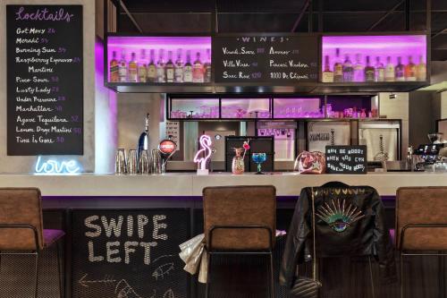 a bar with chairs and a counter with drinks at Moxy Bucharest Old Town in Bucharest