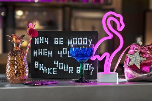 a table with a laptop and a drink glass and a bag at Moxy Bucharest Old Town in Bucharest