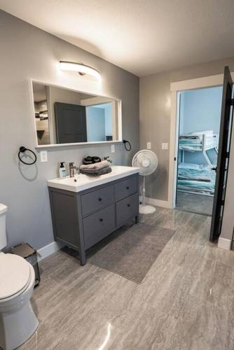 a bathroom with a sink and a toilet and a mirror at Sleeps 40, Pool House in Garden City