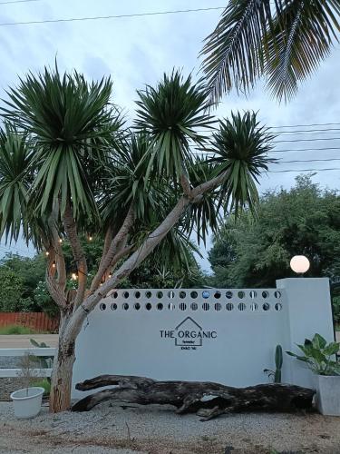 a sign in front of two palm trees at The Organic Farmstay Khoa Yai (ดิ ออร์แกนิค ฟาร์มสเตย์ เขาใหญ่) in Wangkata