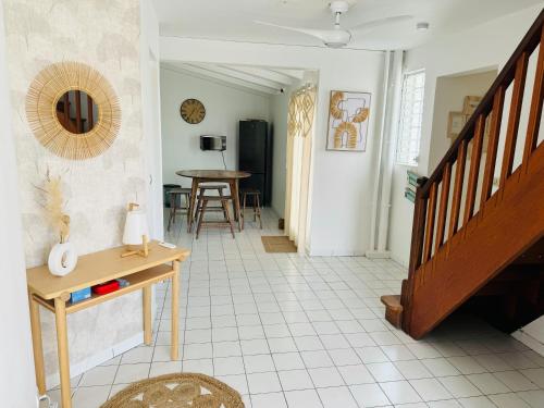 a living room with a staircase and a table at Appartement les Amandines - Centre ville Sainte Anne in Sainte-Anne