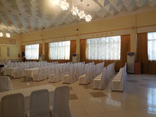 a banquet hall with white chairs and tables and chandeliers at Ust-Kamenogorsk Hotel in Ustʼ-Kamenogorsk