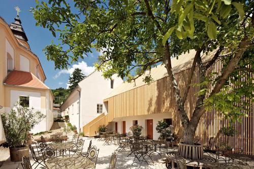 einen Innenhof mit Tischen, Stühlen und einem Baum in der Unterkunft Café FARA in Klentnice