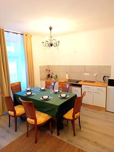 a kitchen with a table with chairs and a green table cloth at 2 room's Family Apartments Mürzzuschlag in Mürzzuschlag
