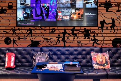 a couch in front of a wall with a tv at Moxy London Stratford in London