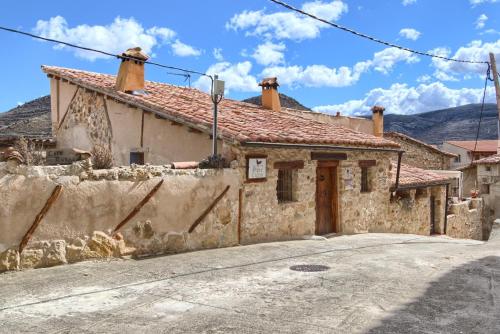 una vieja casa de piedra con una carretera delante de ella en Mirador del Maestrazgo, en Ejulve