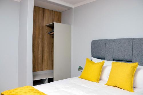 a bedroom with a white bed with yellow pillows at 19 at Sandla in Mbabane