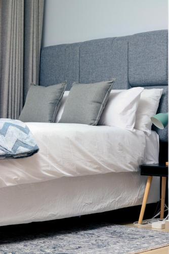a bed with white pillows and a gray headboard at 19 at Sandla in Mbabane
