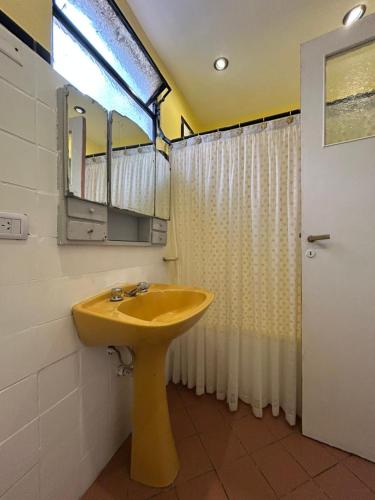een badkamer met een gele wastafel en een spiegel bij Casa Barracas, habitación privada in Buenos Aires