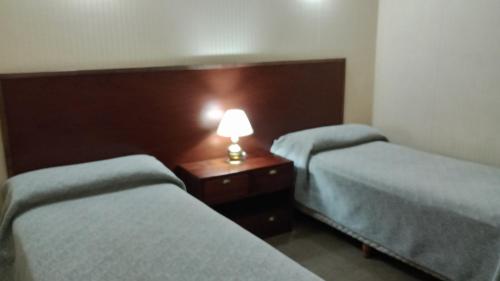 two beds in a room with a lamp on a table at Hotel Centro Naval in Buenos Aires