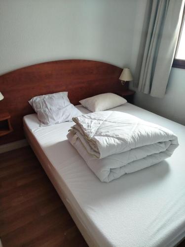 un lit avec des draps blancs et des oreillers dans une chambre dans l'établissement Résidence Le Pic du Midi - maeva Home - Appartement 2 Pièces 4 personnes - Confort MAE-0691, à La Mongie