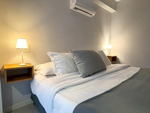 ein Schlafzimmer mit einem Bett mit weißen Laken und Kissen in der Unterkunft Romeo Apt, p/ 4 personas, en el centro de Salta in Salta