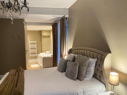 a bedroom with a bed with pillows and a bathroom at UN COCON EN VILLE - chambre SPA chic et élégante in Pacy-sur-Eure