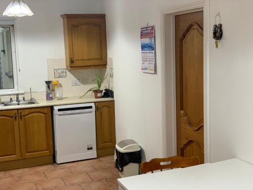 a kitchen with wooden cabinets and a white dishwasher at 4 Bed Room Sharing House in Phibblestown