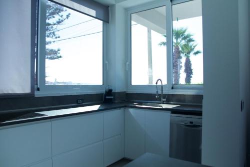a kitchen with white cabinets and two windows at Luxury villa Lucy with pool on front of beach of Donnalucata in Donnalucata