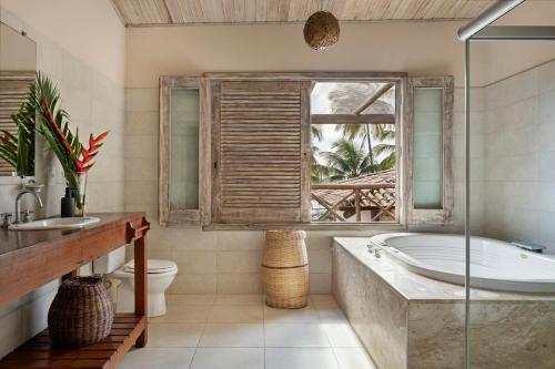 a bathroom with a tub and a toilet and a window at Villa Alema Luxury Beach House in Marau