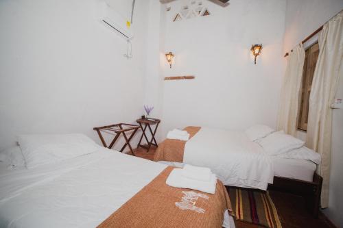 two beds in a room with white sheets at Hotel Archangelus in Mompós