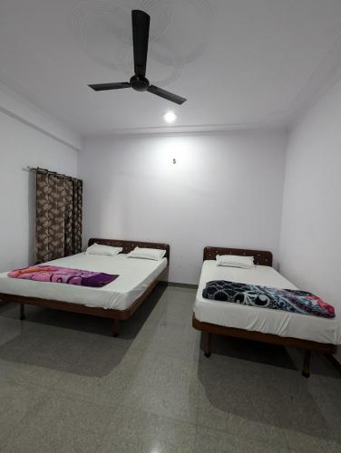 two beds in a room with a ceiling fan at Hotel Raghunath Palace in Khātu