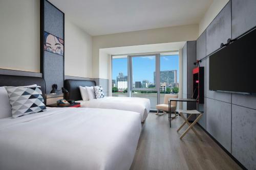 a hotel room with two beds and a flat screen tv at Moxy Ningbo Old Bund in Ningbo